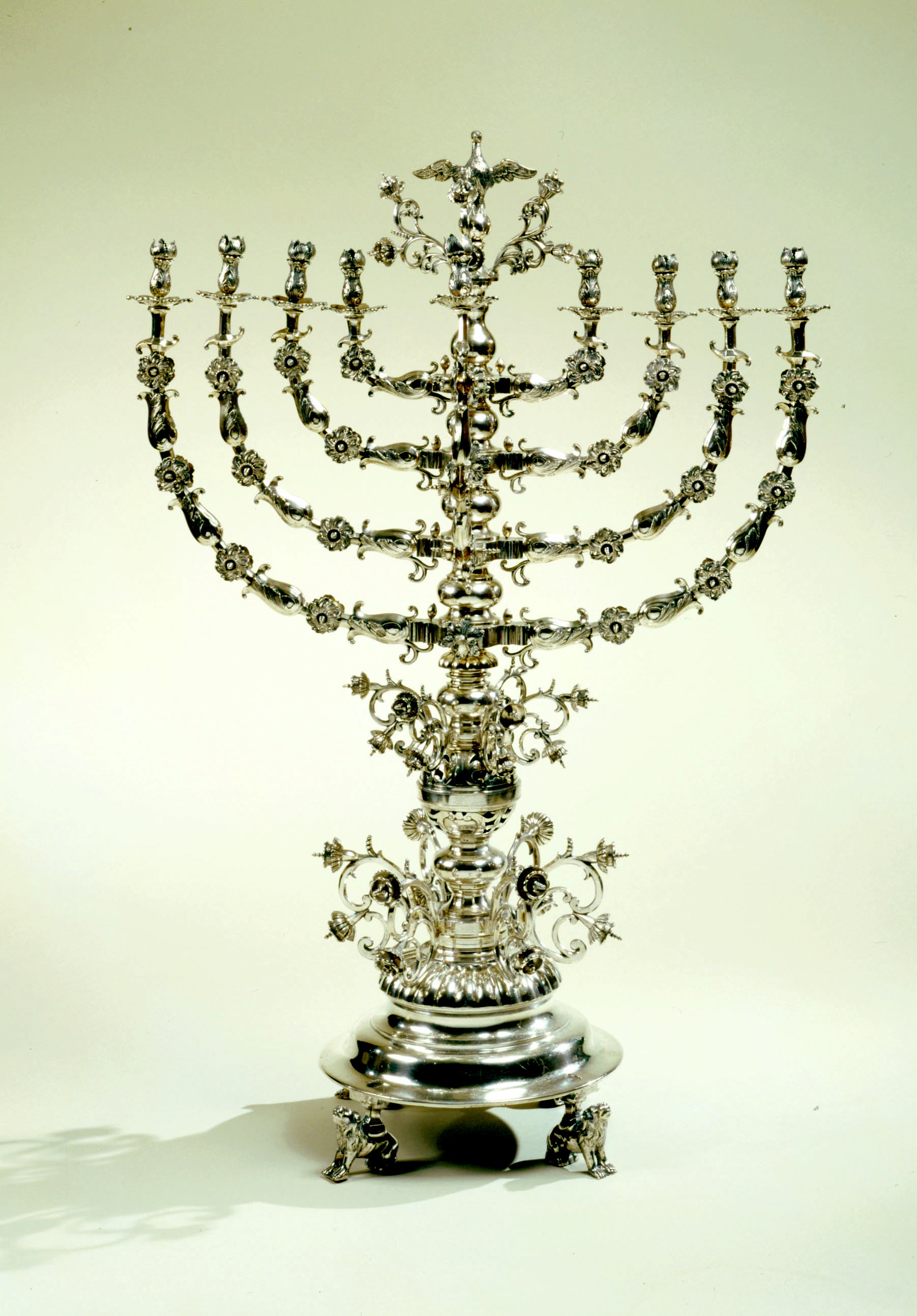 上图:19世纪乌克兰的光明节灯台Hanukkah menorah。主前168年,安提阿古四世强制推行希腊化,在圣殿里竖起宙斯祭坛,用猪献祭,并强迫犹太人吃猪肉,导致了马加比起义。犹大马加比收复耶路撒冷以后,下令洁净圣殿,庆祝八天「修殿节」。当时人们在圣殿里只找到一罐有大祭司封印的用于点燃金灯台的灯油,无论是制作还是去外地取来这种专门洁净过的灯油,都需要八天时间。但这罐只能燃用一天的灯油,竟然一直燃烧了八天。为纪念此事,修殿节最主要的仪式是点燃九枝灯台,中间的灯盏用来点燃其它八支灯盏,每天多点一枝,一直到第八天,所以「修殿节」也被称为「光明节」。